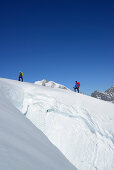 Two mountaineers ascending in front of a crevasse to Piz Palue, Grisons, Switzerland
