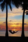 Woman in hammock, and palm trees at sunset, Coral Coast, Viti Levu, Fiji, South Pacific