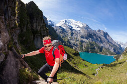 A man hiking, mountaineering above lake Oeschinen, Bernese Oberland, Canton of Bern, Switzerland