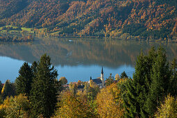 View over autumnal trees onto the church at lake Schliersee, Upper Bavaria, Germany, Europe