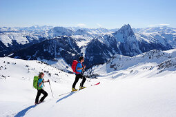 Two backcountry skiers ascending to Brechhorn, Grosser Rettenstein in background, Kitzbuehel Alps, Tyrol, Austria