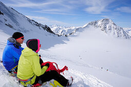 Two backcountry skiers resting during ascent to Wildspitze, Oetztal Alps, Tyrol, Austria