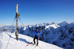Young man removing skins from backcountry ski, summit of Pyramidenspitze, Kaiser-Express, Zahmer Kaiser, Kaiser mountain range, Tyrol, Austria