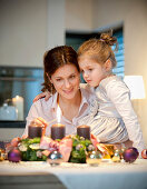 Mutter und Tochter (4 Jahre) zünden Adventskranz an, Steiermark, Österreich