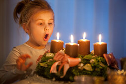 Mädchen (4 Jahre) will Kerzen am Adventskranz ausblasen, Steiermark, Österreich