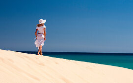 Junge Frau mit Hut geht auf Düne spazieren, Playa de Sotavento, Sotavento, Costa Calma, Jandia, Morro Jable, Fuerteventura, Kanarische Inseln, Spanien, Europa