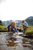 Children playing in a stream along the Nassfeld National Park trail, Nassfeld alp, Gastein valley, Bad Gastein, St. Johann im Pongau, Salzburg, Austria