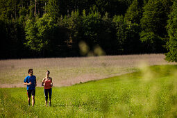 Two joggers running over a meadow, Upper Bavaria, Germany