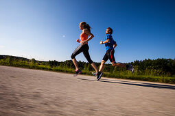 Two people jogging along a road, Upper Bavaria, Germany