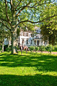 Women on a horse in front of Gut Immenhof known from the movies the Immenhof, Malente, Schleswig-Holstein, Germany