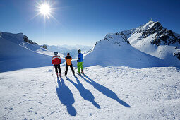 Drei Skifahrer betrachten Aussicht vom Mattunjoch auf Valluga, Lechtaler Alpen, Arlberg, Österreich