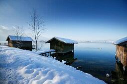 Snow-covered boathouses at lake Kochel, Upper Bavaria, Germany