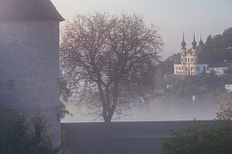 Marienberg fortress surounded by fog and Capuchin cloister Kaeppele, Wuerzburg, Bavaria, Germany