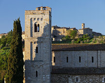 Abtei Sant Antimo mit Zypresse und Häuser im Hintergrund, Castelnuovo Dellabate, Toskana, Italien