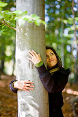 Junge Frau umarmt einen Baum, Steiermark, Österreich