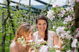 Two young women between flowering apple trees, Riegersburg, Styria, Austria