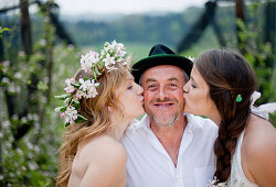 Zwei junge Frauen küssen Obstbauer, Riegersburg, Steiermark, Österreich