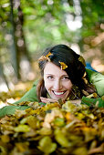 Junge Frau liegt im Herbstlaub, Steiermark, Österreich