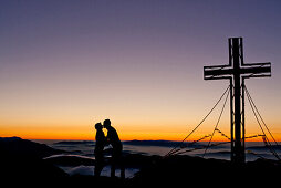 Two hikers at summit of Hochschwab mountain at sunrise, Hochschwab, Styria, Austria