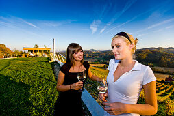 Zwei junge Frauen trinken Weißwein auf einem Weingut, Gamlitz, Steiermark, Österreich