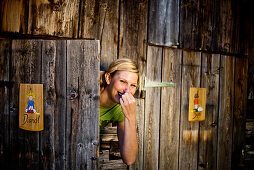 Junge Frau schaut hinter einer Toilettentür hervor, Duisitzkarsee, Steiermark, Österreich