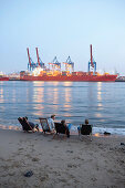 Guests on the beach near Cafe Strandperle in Hamburg-Oevelgoenne, the HHLA container terminal is situated on the opposite bank of the Elbe, Hamburg harbour, Hamburg, Germany