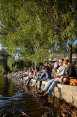 People sitting on the seawall at Alsterperle Cafe and bar, Eduard-Rhein-Ufer 1, Outer Alster Lake, Hamburg, Germany