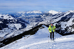 Female back-country skier ascending to Grosser Schuetz, Kaiser mountain range in background, Kitzbuehel Alps, Tyrol, Austria