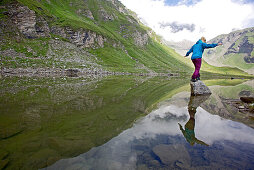 Junge Frau steht auf einem Stein im Fluss Soca, Alpe-Adria-Trail, Tolmin, Slowenien