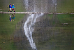 Zwei Wanderinnen überqueren Faaker-See auf einem Pfad, Kärnten, Österreich