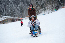 Mann mit Gehbehinderung fährt mit Begleiterin auf Piste Ski, Söll, Kitzbüheler Alpen, Tirol, Österreich
