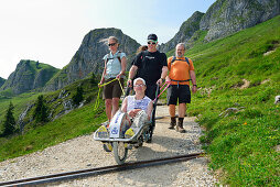 Gruppe von Wanderern begleitet Mann im Rollstuhl, Bergtour mit Behinderten, Rotwand, Spitzing, Bayerische Alpen, Oberbayern, Bayern, Deutschland
