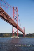 Kanuten vor der Brücke Ponte 25 de Abril über den Fluss Tejo mit Christusstatue in der Distanz, Lissabon, Portugal