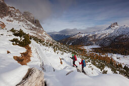 Junges Paar wandert im Schnee, Naturpark Fanes-Sennes-Prags, Tal des Passo di Falzarego, Dolomiten, Belluno, Venetien, Italien