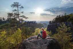 Junge Frau sitzt auf einem Felsen und genießt die Aussicht, Nationalpark Sächsische Schweiz, Sachsen, Deutschland