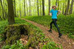 Young woman jogging through a beech forest, National Park Hainich, Thuringia, Germany