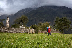 Junge Frau mit Rucksack wandert, Soglio, Bergell, Kanton Graubünden, Schweiz