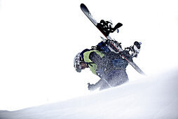 Junger Snowboarder steigt durch den Schnee in den Bergen bei Schneefall, Pitztal, Tirol, Österreich