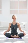 Gesunde junge Frau in der Yogaposition der glücksverheißenden Pose