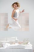 Attractive young woman jumping on her bed