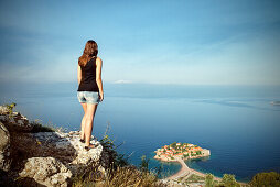 Junge Frau genießt den Panorama Ausblick auf die Luxus Hotel Insel Sveti Stefan, Adria Mittelmeerküste, Montenegro, Balkan Halbinsel, Europa