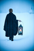 Woman carrying a lantern through snow, Styria, Austria