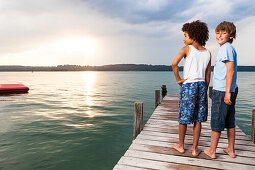 Two boys on a jetty at lake Starnberg, Upper Bavaria, Germany