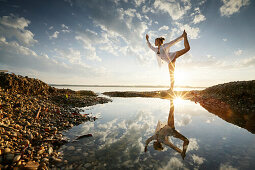 Woman practicing yoga at lake Starnberg, Upper Bavaria, Germany
