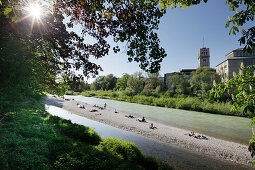 People sunbathing at river Isar, Deutsches Museum in background, Munich, Bavaria, Germany