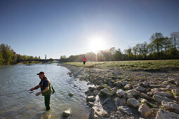 Angler and jogger at river Isar, Wittelsbach bridge in background, Munich, Bavaria, Germany