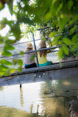 Two young women sitting on a jetty at river Rhine, Rheinfelden, Baden-Wuerttemberg, Germany