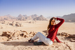 Frau rastet auf Felsen, Wadi Rum, Jordanien, Naher Osten