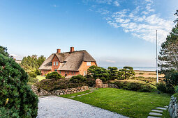 Thatched-roof house with Wadden Sea in background, Kampen, Sylt, Schleswig-Holstein, Germany