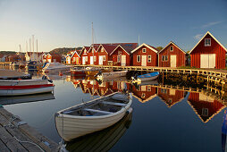 Boats and boot houses in Bleket port, with reflection in the water, Tjoern Island, Province of Bohuslaen, West coast, Sweden, Europe